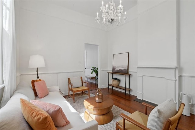 living area with wood finished floors, a wainscoted wall, and a chandelier