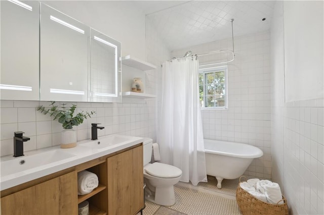 bathroom with a sink, a freestanding bath, tile walls, and tile patterned floors