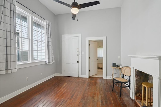 living area featuring baseboards, a fireplace, a ceiling fan, and hardwood / wood-style flooring