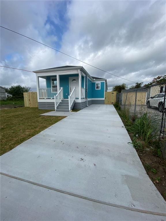 4612 Majestic Oaks Dr, New Orleans, LA 70126 - view of front of house with a front lawn, concrete driveway, fence, and covered porch