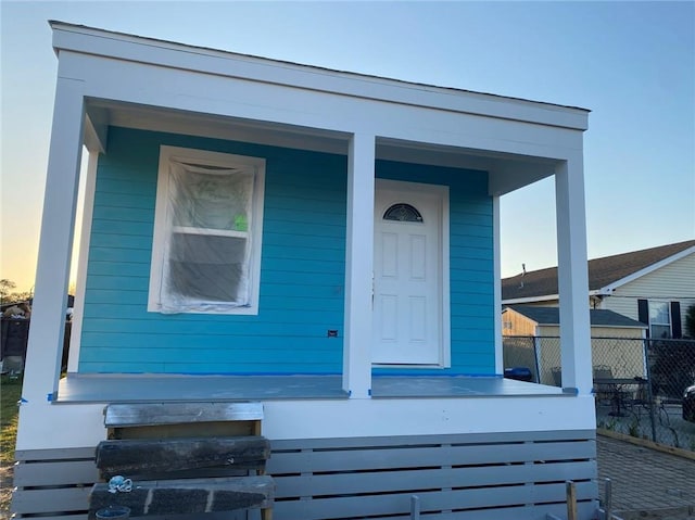 doorway to property with fence and covered porch