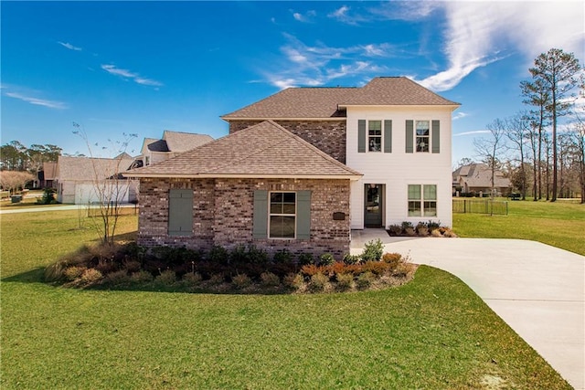 traditional-style home with brick siding, driveway, a front lawn, and roof with shingles