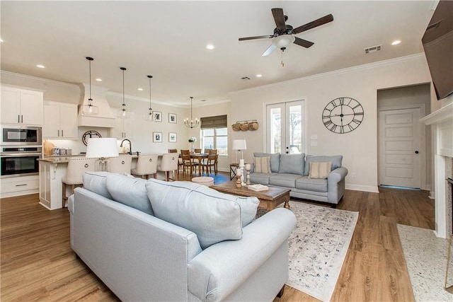 living room featuring wood finished floors, baseboards, visible vents, a premium fireplace, and ornamental molding