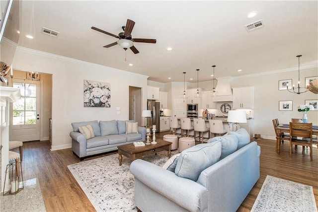 living room with wood finished floors, visible vents, and baseboards