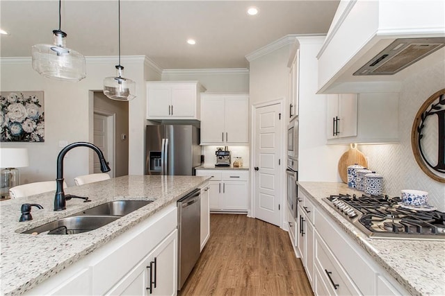 kitchen with premium range hood, ornamental molding, light wood-style floors, stainless steel appliances, and a sink