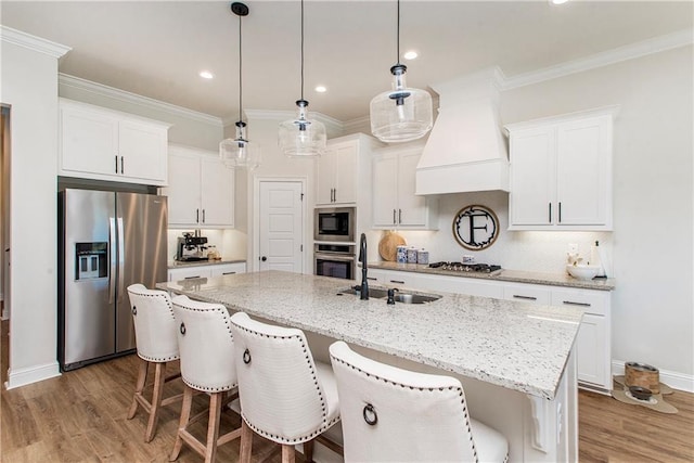 kitchen with ornamental molding, a sink, white cabinetry, appliances with stainless steel finishes, and custom exhaust hood