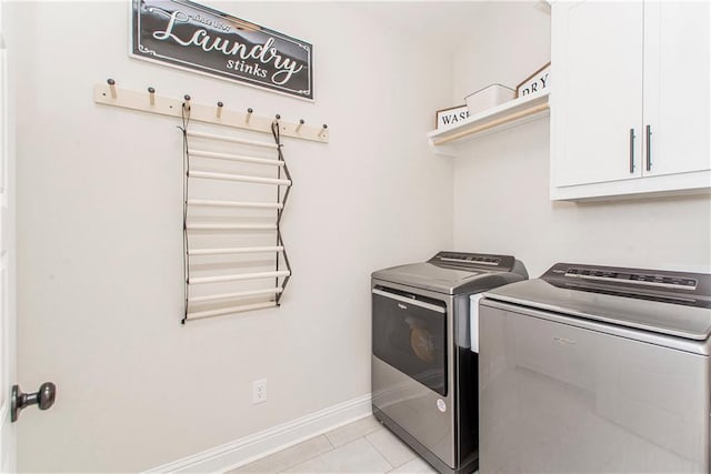 clothes washing area with cabinet space, light tile patterned floors, washer and dryer, and baseboards