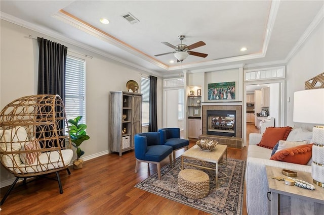 sitting room with visible vents, a ceiling fan, a tray ceiling, wood finished floors, and crown molding