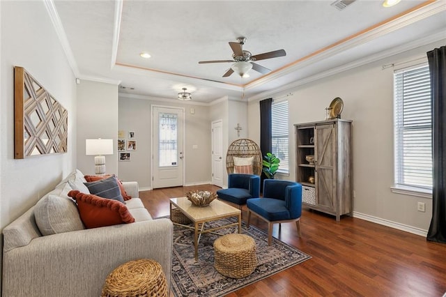 living area featuring crown molding, ceiling fan, baseboards, a tray ceiling, and wood finished floors