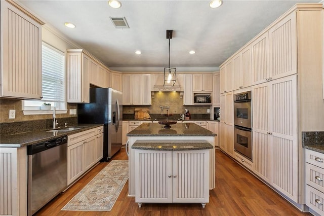 kitchen featuring a sink, dark stone countertops, tasteful backsplash, dark wood finished floors, and appliances with stainless steel finishes