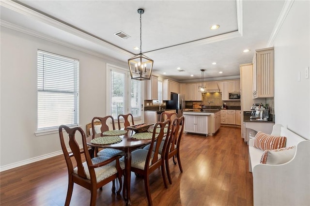 dining area with wood finished floors, baseboards, visible vents, crown molding, and a notable chandelier