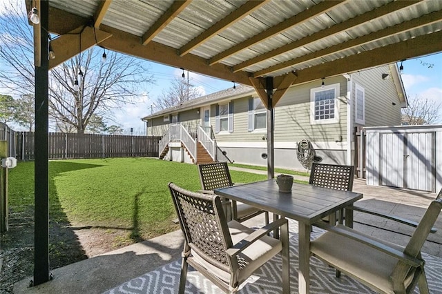 view of patio with outdoor dining area, a fenced backyard, a wooden deck, and stairs