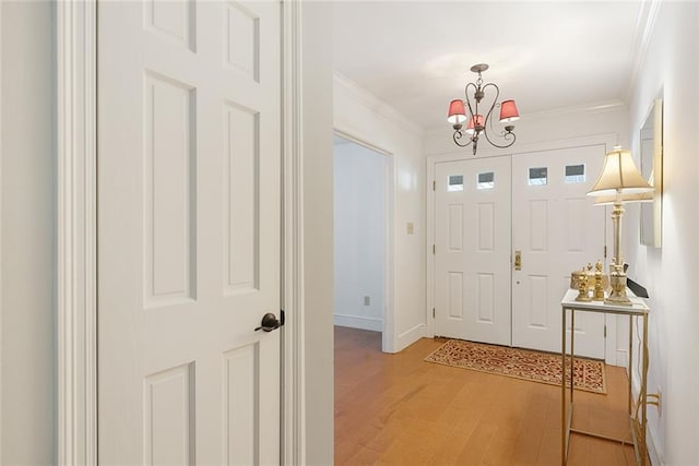 entryway with a notable chandelier, light wood-style flooring, baseboards, and ornamental molding