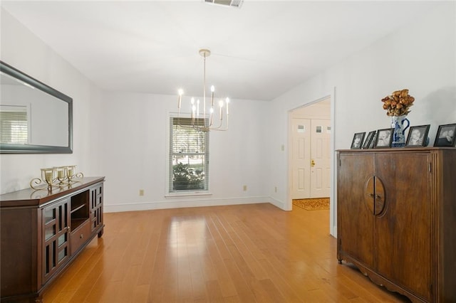 dining space featuring visible vents, an inviting chandelier, baseboards, and light wood-style floors