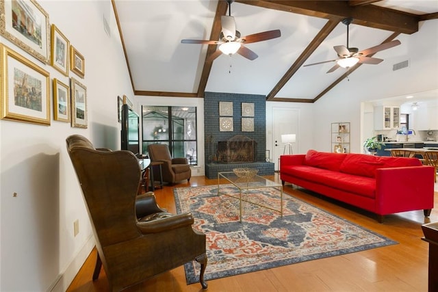 living room with visible vents, a brick fireplace, beam ceiling, wood finished floors, and high vaulted ceiling