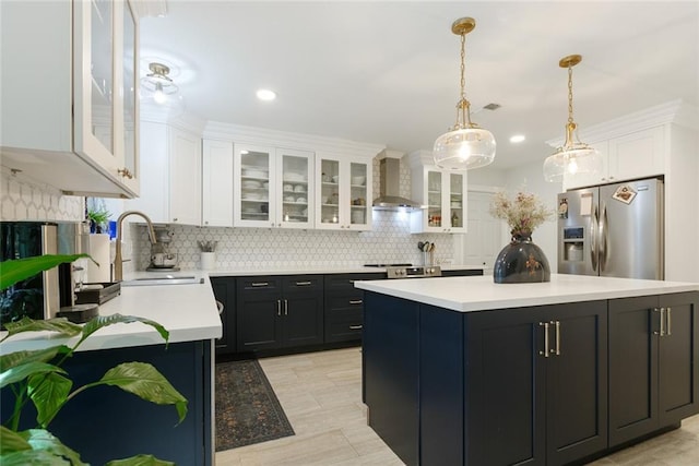 kitchen with a sink, wall chimney exhaust hood, stainless steel fridge with ice dispenser, and white cabinetry