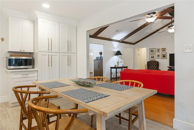 dining space with vaulted ceiling with beams, a ceiling fan, and light wood finished floors