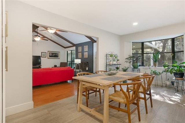 dining space featuring lofted ceiling, a ceiling fan, light wood-type flooring, and baseboards