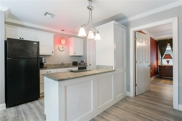 kitchen with visible vents, white cabinets, crown molding, and freestanding refrigerator