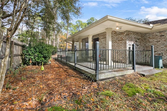 view of property exterior featuring brick siding and fence