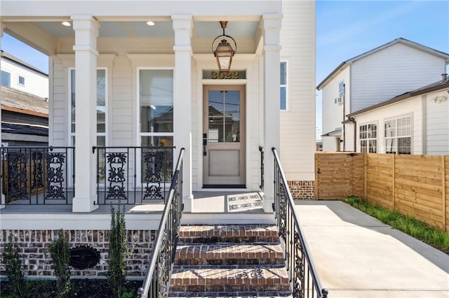 property entrance with covered porch and fence