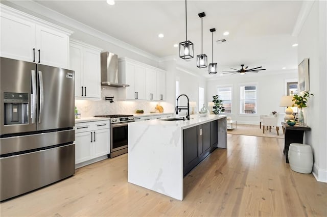 kitchen with wall chimney range hood, ornamental molding, decorative backsplash, appliances with stainless steel finishes, and a sink