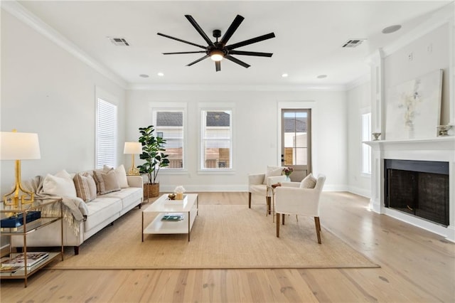 living room with wood finished floors, a fireplace, visible vents, and ornamental molding