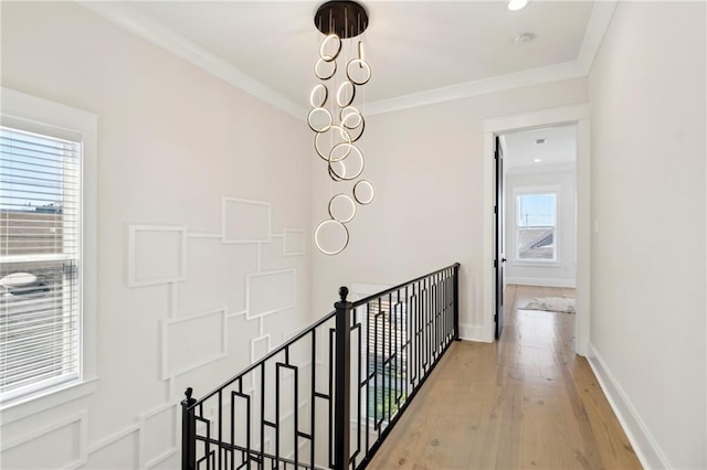 hallway featuring baseboards, an upstairs landing, light wood-style floors, and ornamental molding