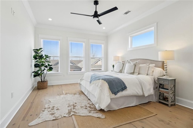 bedroom featuring visible vents, baseboards, wood finished floors, and crown molding