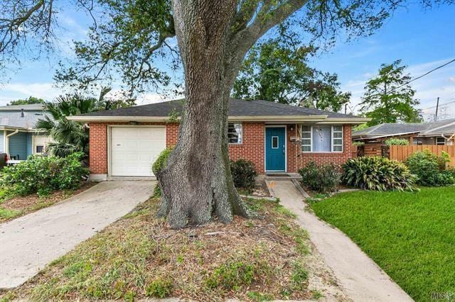 ranch-style home with brick siding, a front lawn, fence, concrete driveway, and an attached garage