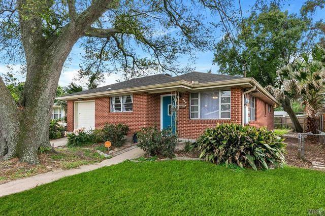 view of front of house with an attached garage, brick siding, fence, and a front yard