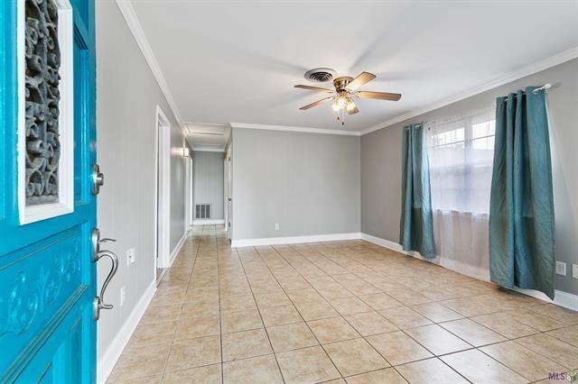 entryway with light tile patterned floors, visible vents, ornamental molding, and ceiling fan