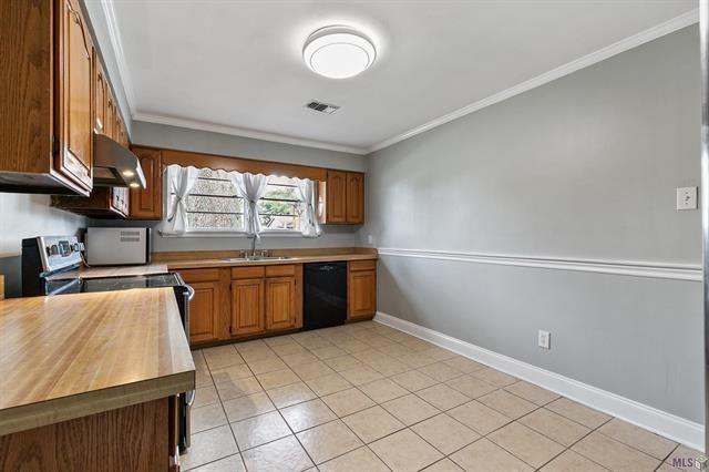 kitchen featuring visible vents, a sink, under cabinet range hood, dishwasher, and crown molding