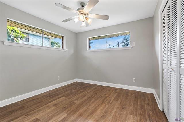 unfurnished bedroom featuring a closet, ceiling fan, baseboards, and wood finished floors