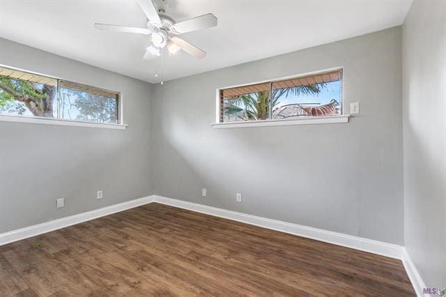 spare room with wood finished floors, a ceiling fan, and baseboards