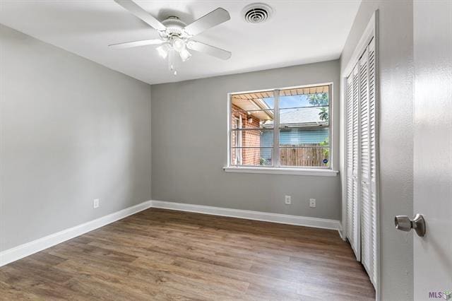 empty room with visible vents, ceiling fan, baseboards, and wood finished floors