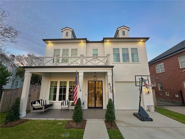 back of house with a balcony, fence, driveway, a porch, and an attached garage