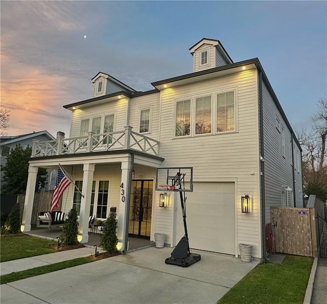 view of front facade featuring concrete driveway, an attached garage, fence, and french doors