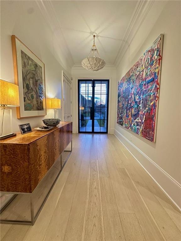 hall with a chandelier, baseboards, light wood-style floors, and ornamental molding