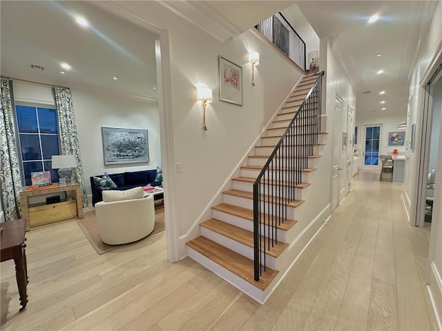 stairway featuring baseboards, hardwood / wood-style floors, and crown molding