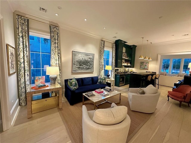 living room with light wood-type flooring, visible vents, ornamental molding, and recessed lighting