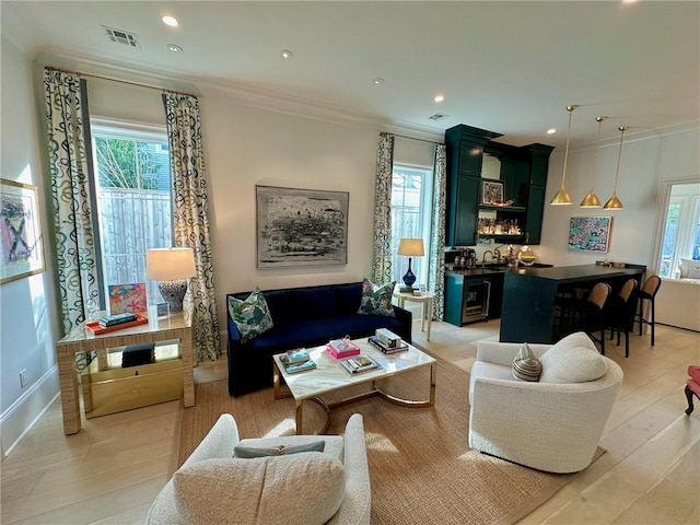 living room featuring visible vents, recessed lighting, light wood-style floors, and ornamental molding