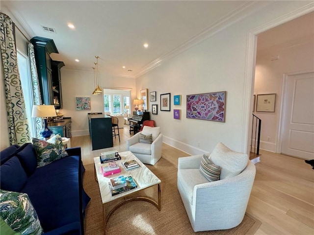 living room with baseboards, light wood-style floors, visible vents, and ornamental molding