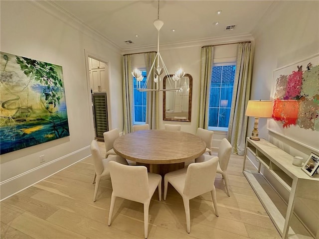 dining space with visible vents, light wood-style flooring, baseboards, and ornamental molding