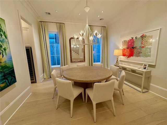 dining area with visible vents, crown molding, baseboards, a chandelier, and light wood-style flooring