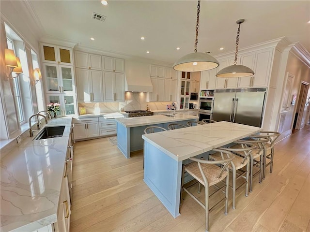 kitchen featuring visible vents, a large island, appliances with stainless steel finishes, custom exhaust hood, and a sink