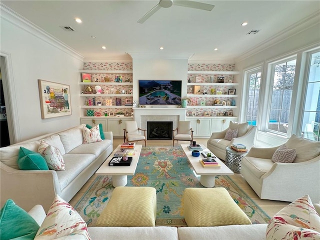 living area with built in features, a fireplace, visible vents, and ornamental molding