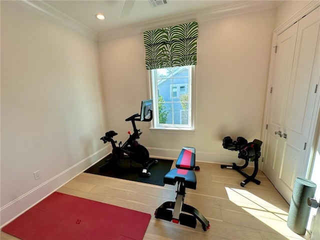 exercise room featuring visible vents, wood finished floors, baseboards, and ornamental molding