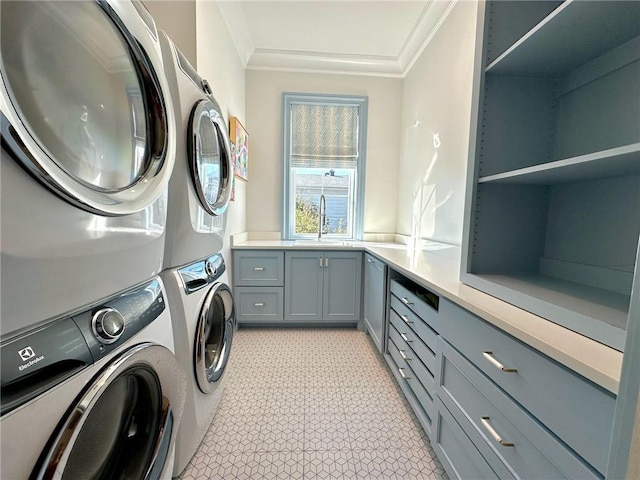 clothes washing area featuring light floors, ornamental molding, stacked washing maching and dryer, cabinet space, and a sink