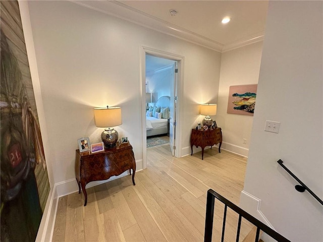 sitting room featuring light wood-type flooring, baseboards, an upstairs landing, and crown molding